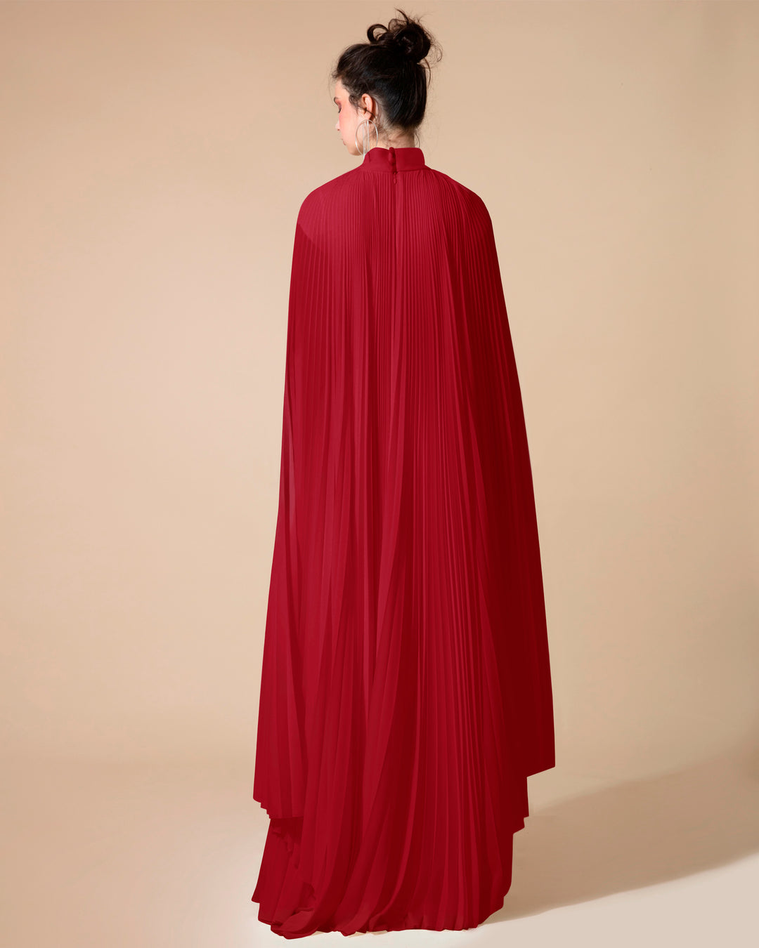 The back of a fully pleated flared chiffon red kaftan dress with cape-like asymmetrical sleeves.