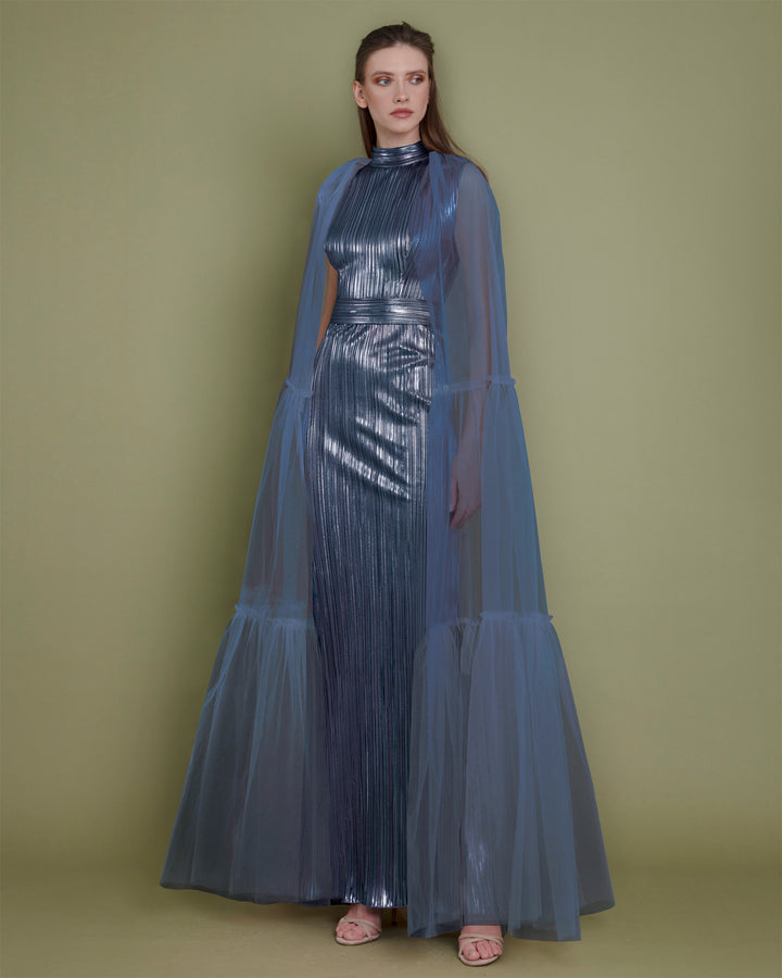 A slim cut metallic blue evening dress in pleated fabric paired with a tulle ruffled cape.