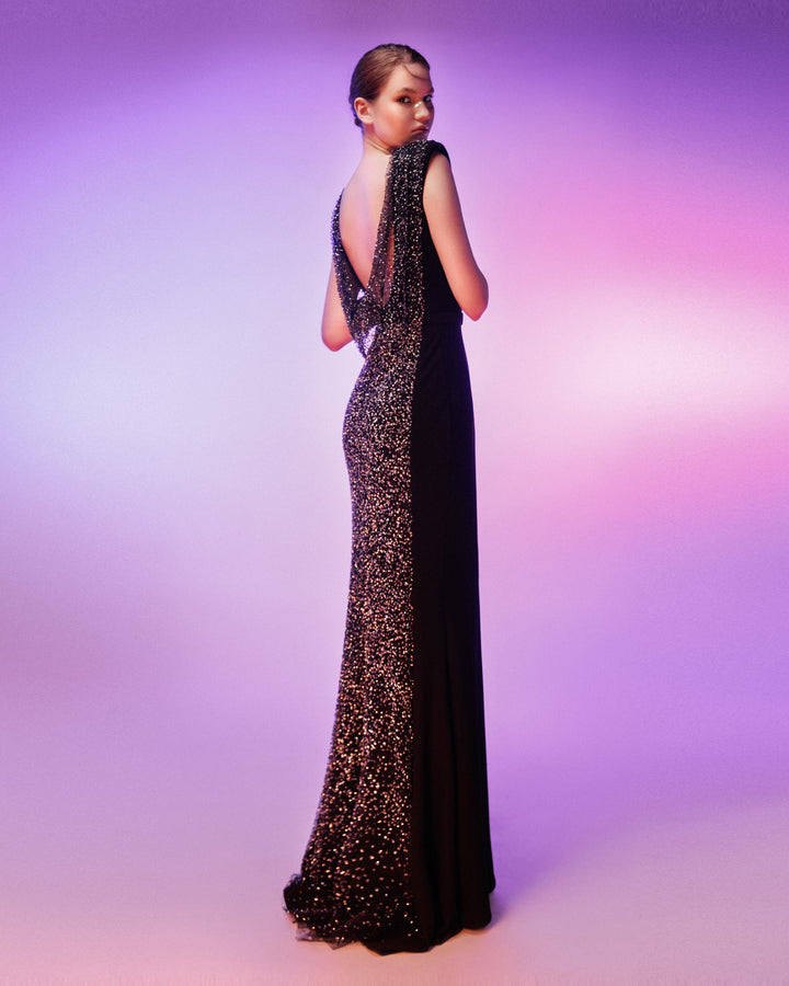 The back of a padded shoulders slim-cut black evening dress featuring an open draped back and a full back overlayed with beaded see-through fabric. 