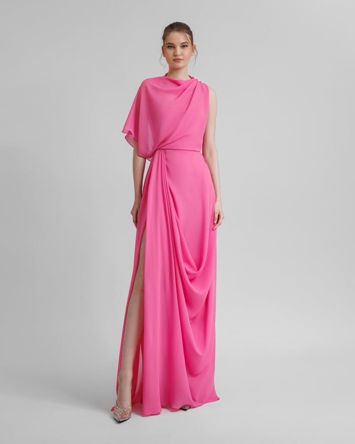 An asymmetrical pink chiffon evening dress with draping details featuring a slit on the side.