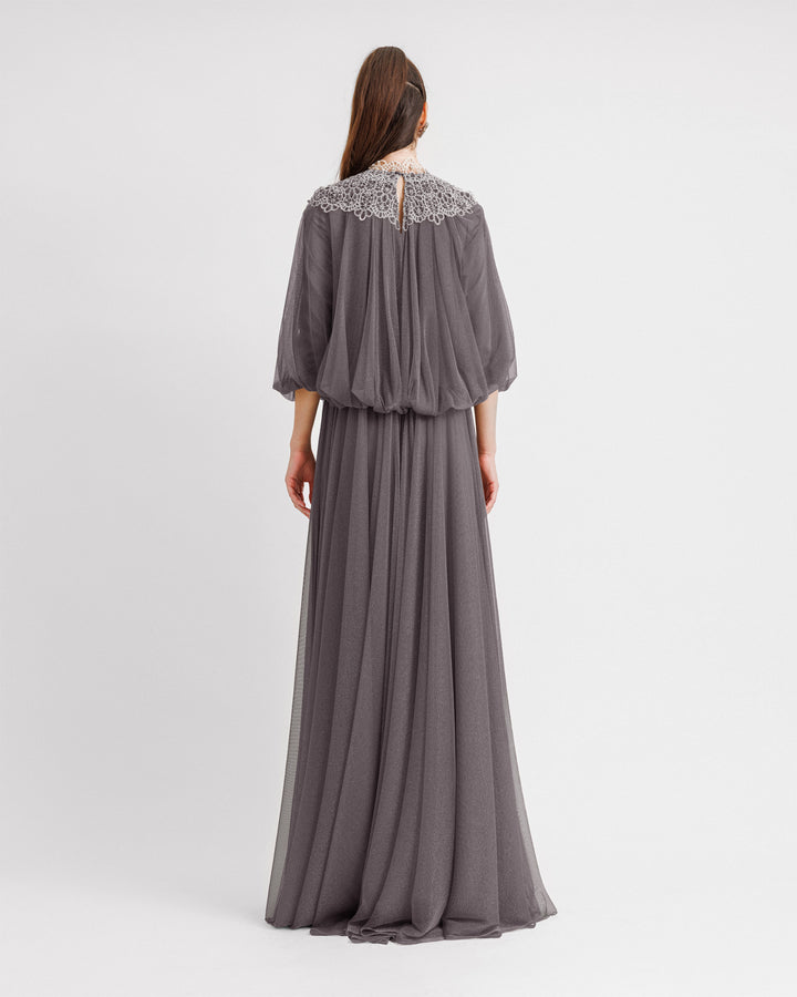 The back of a kaftan-style loose-cut grey evening dress with lace at the neckline, gathered waist at the back, and three-quarter bishop sleeves.