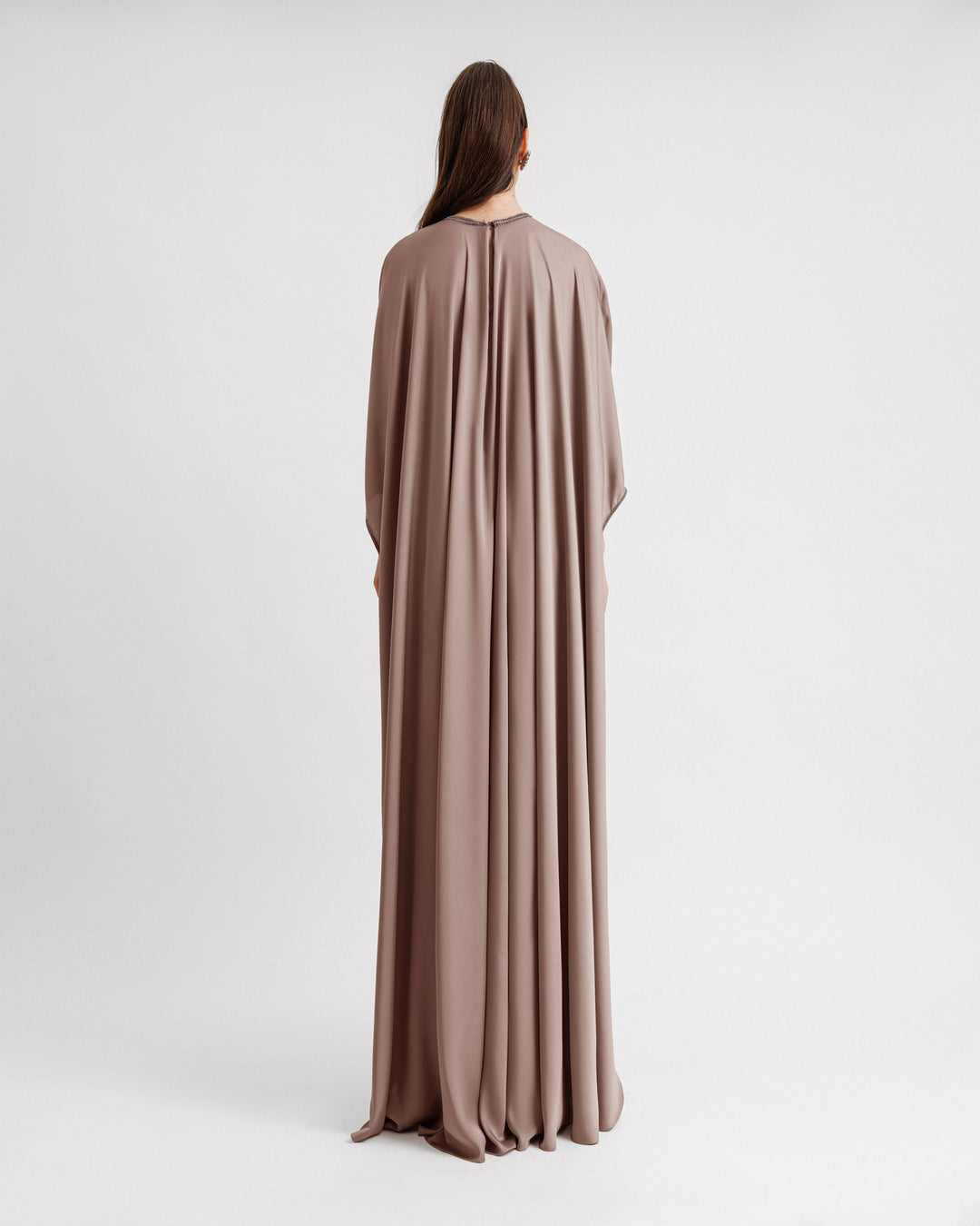 The back of a kaftan-style evening dress in taupe color with a beaded neckline and three-quarters sleeves.