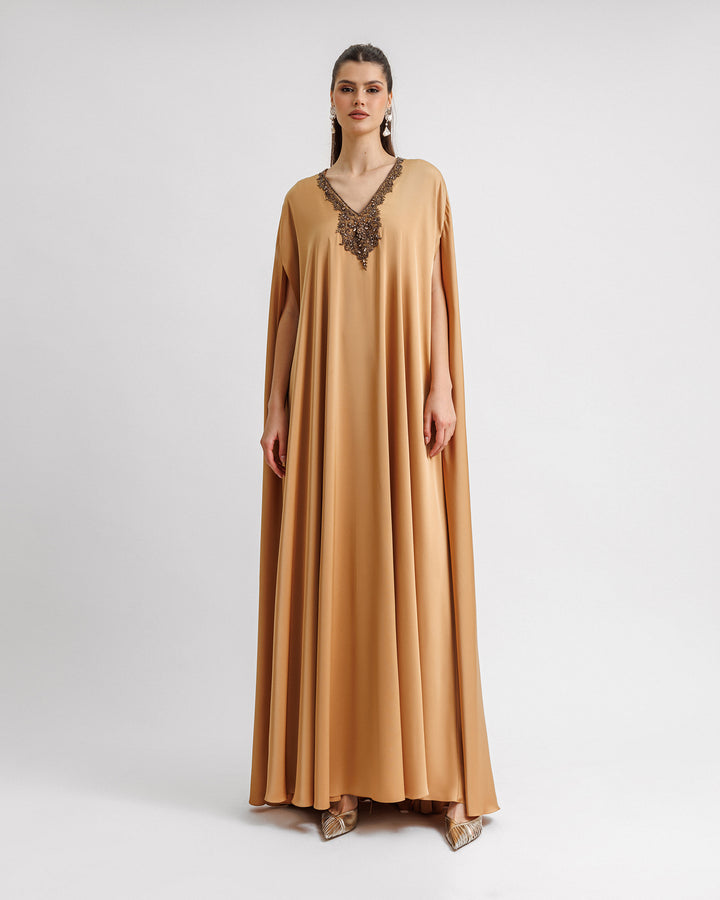 A caramel color kaftan-style evening dress with a beaded V-neckline.