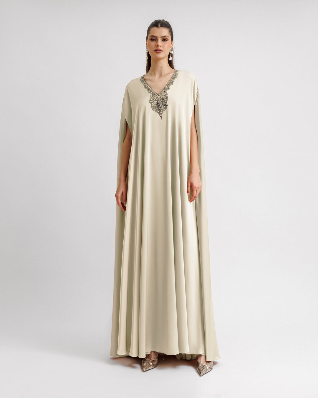 A cream color satin Kaftan-style dress with a beaded V-neckline.