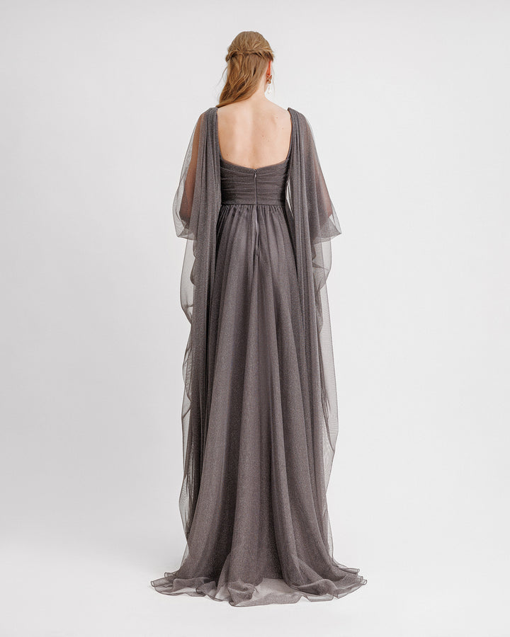 The back of a grey tulle evening dress with ruffled floor-length sleeves, a slightly open back, and a draped waistline.