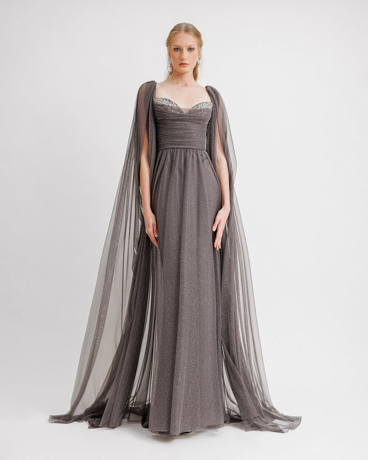 A beaded heart-neckline grey tulle evening dress with ruffled floor-length sleeves and a draped waistline.