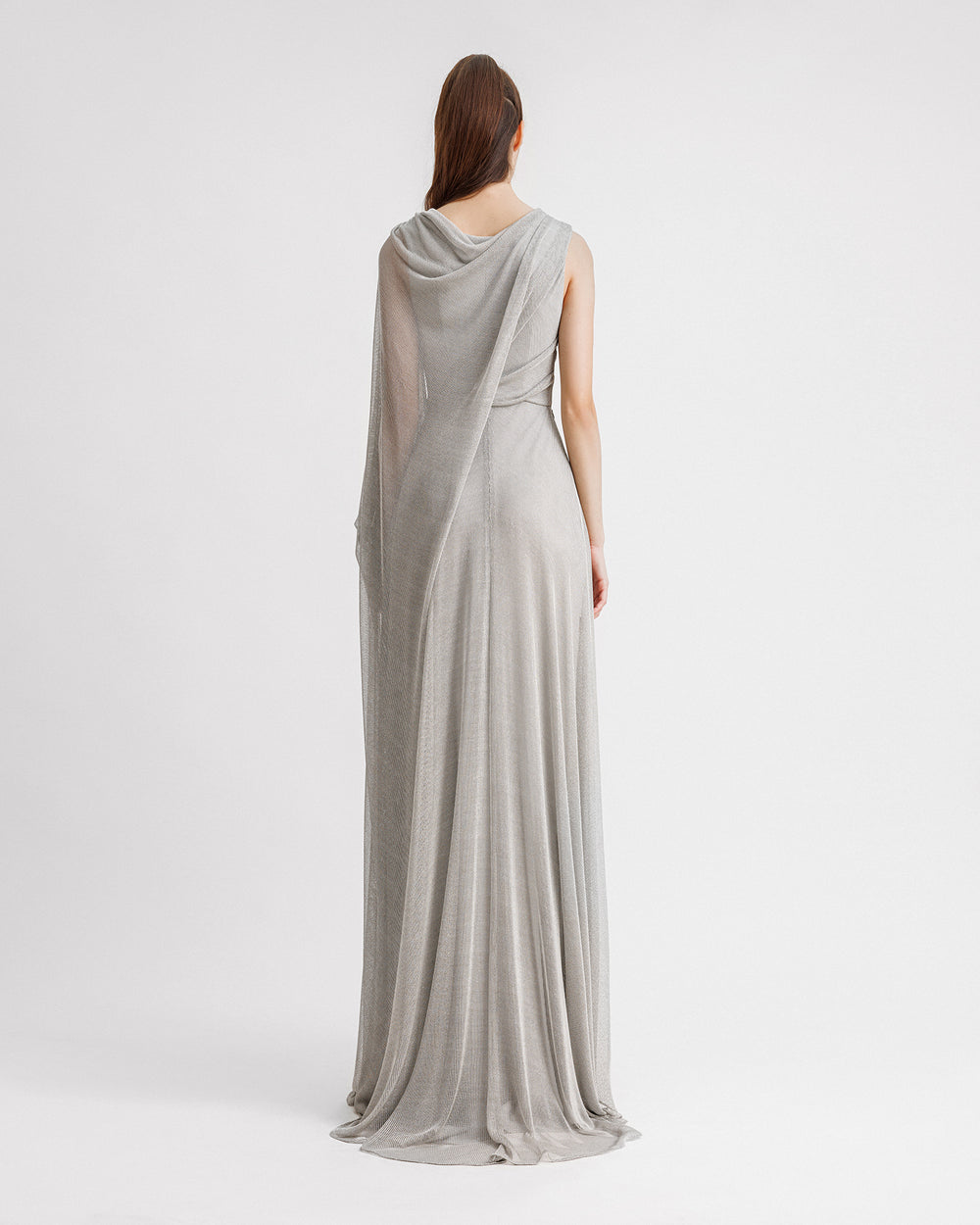 The back of a V-neckline silver evening dress in net tulle with a long draped cape-like one sleeve.