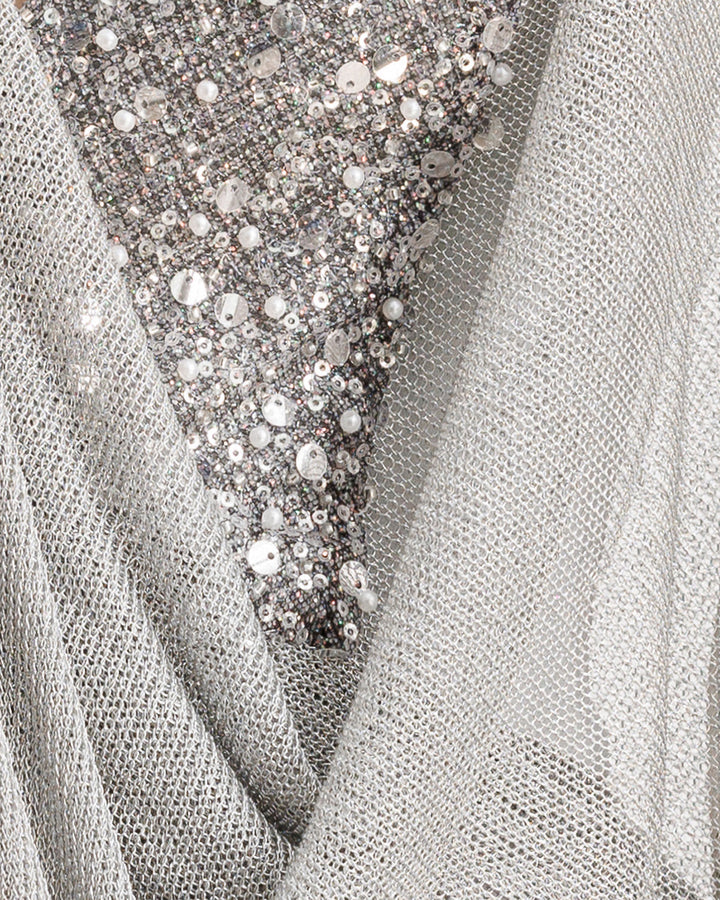 A close-up of a silver net tulle fabric overlaying a beaded fabric.