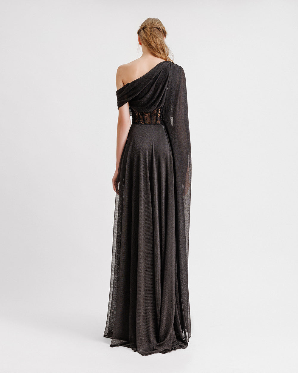 The back of an asymmetrical neckline draped black dress with a structured see-through corset.