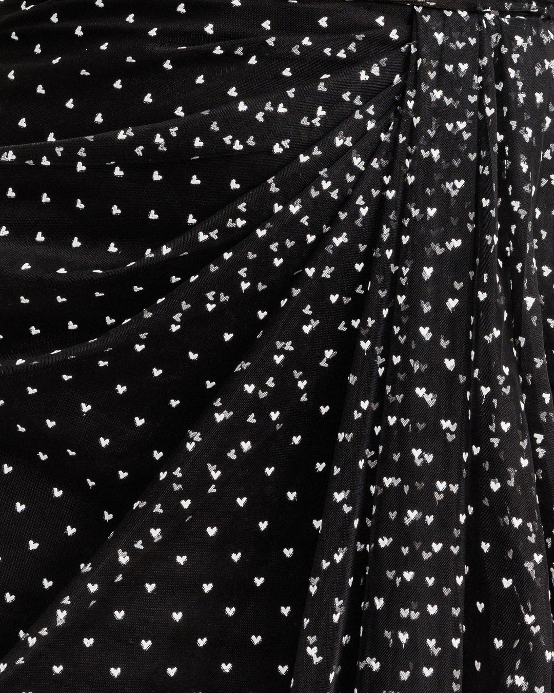 A close up of a black tulle draping detail with mini white heart pattern.