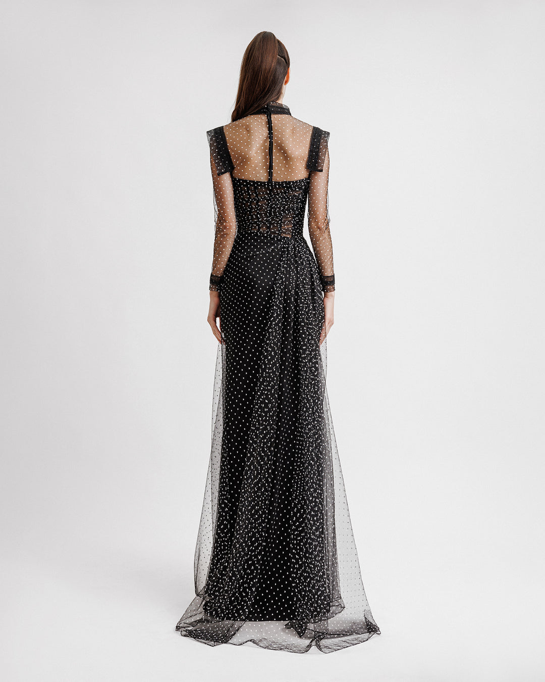 The back of a strapless draped black dress with a slit on the side, paired with a detachable see-through long sleeve top.