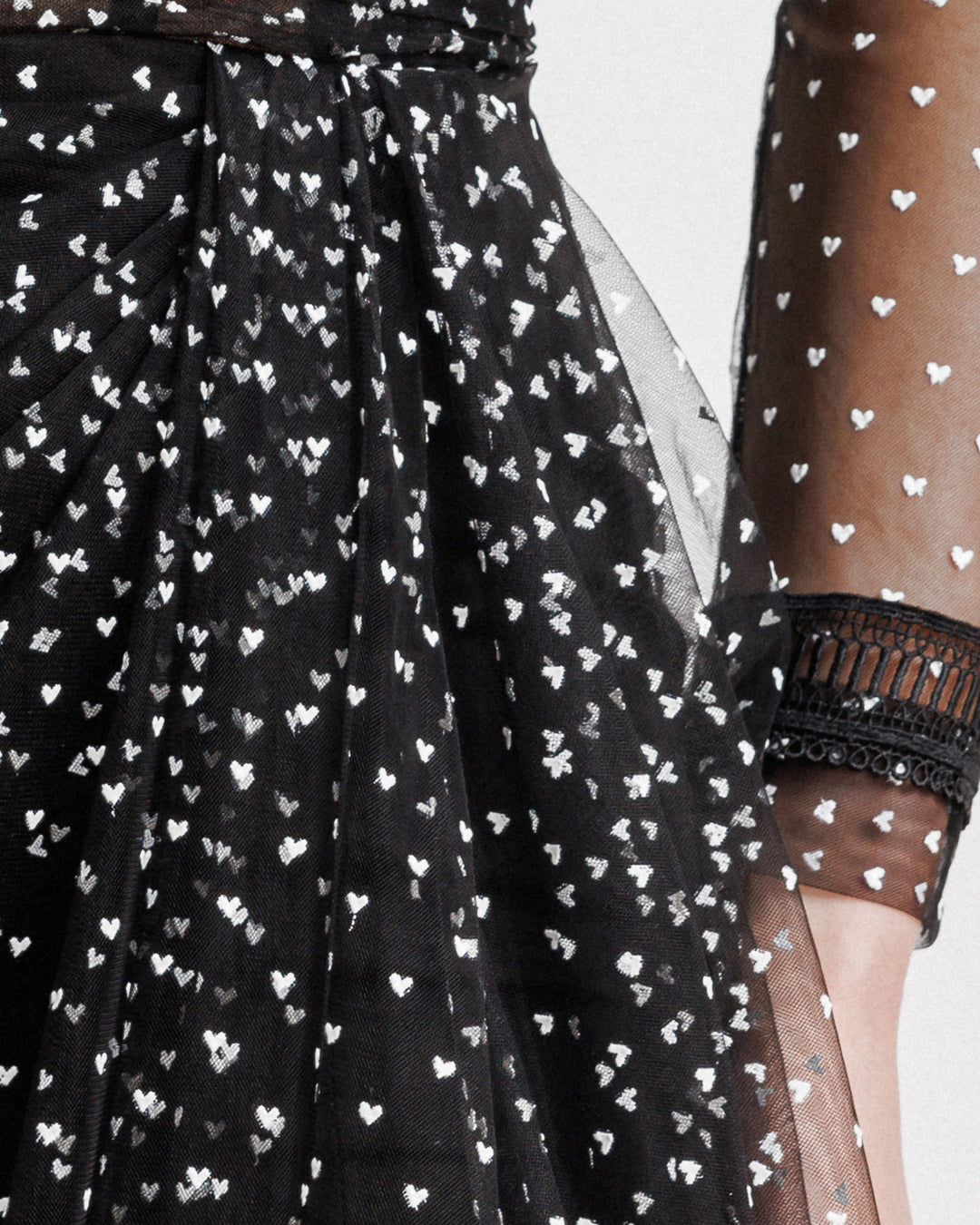 A close-up of white heart dotted black dress with embroidery details on the sleeve. 