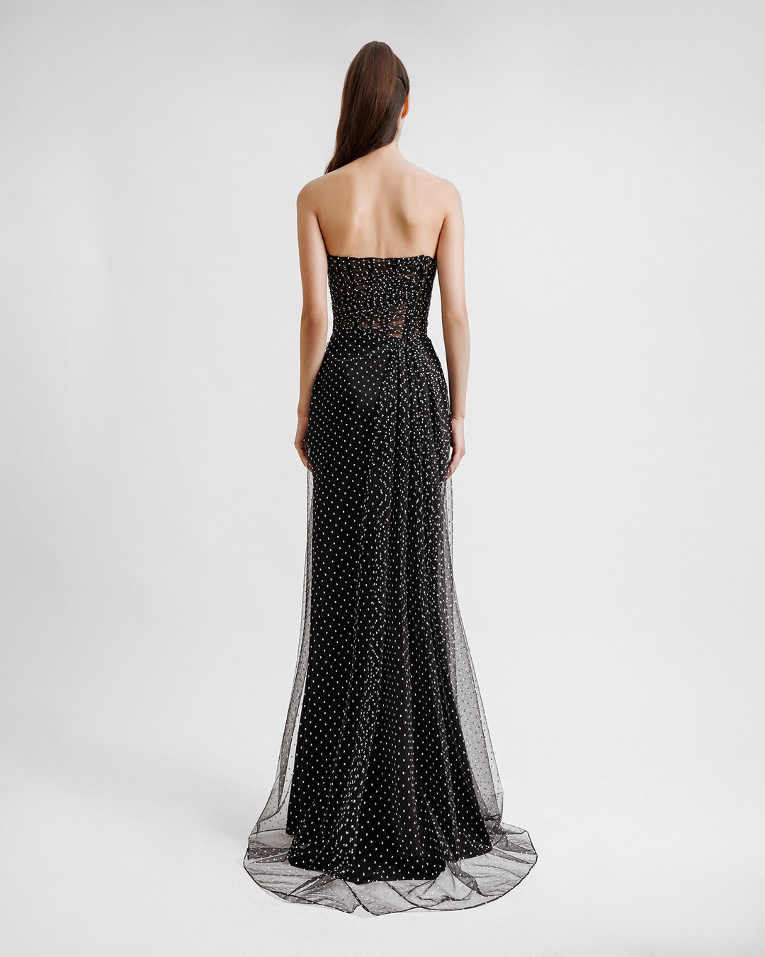 The back of a strapless draped black dress with a slit on the side and mini white heart pattern..