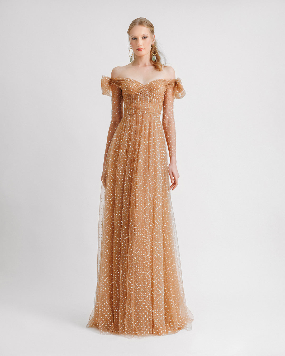 An off-the-shoulders caramel evening dress in white heart pattern tulle with a draped neckline and see-through sleeves.