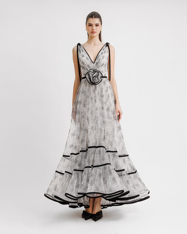 A V-neckline black dotted white tulle evening dress with a flowy structured skirt and a draped flower at the waist.