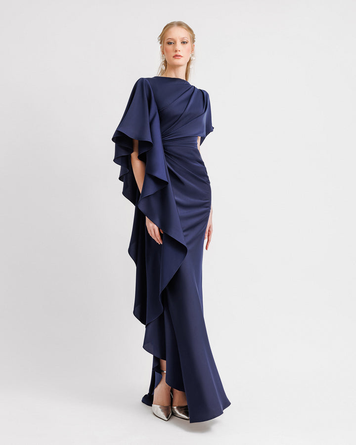 An asymmetrical draped navy evening dress with a ruffled sleeve going all the way down to the hemline and a slit on the side.