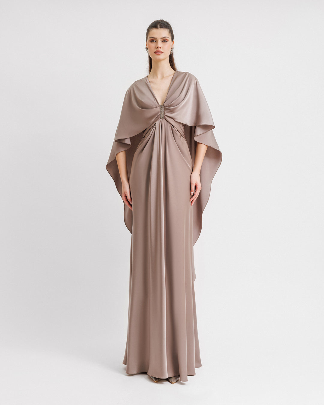 A V-neckline draped satin evening dress in taupe color with ruffled cape-like sleeves and beadings at the front.