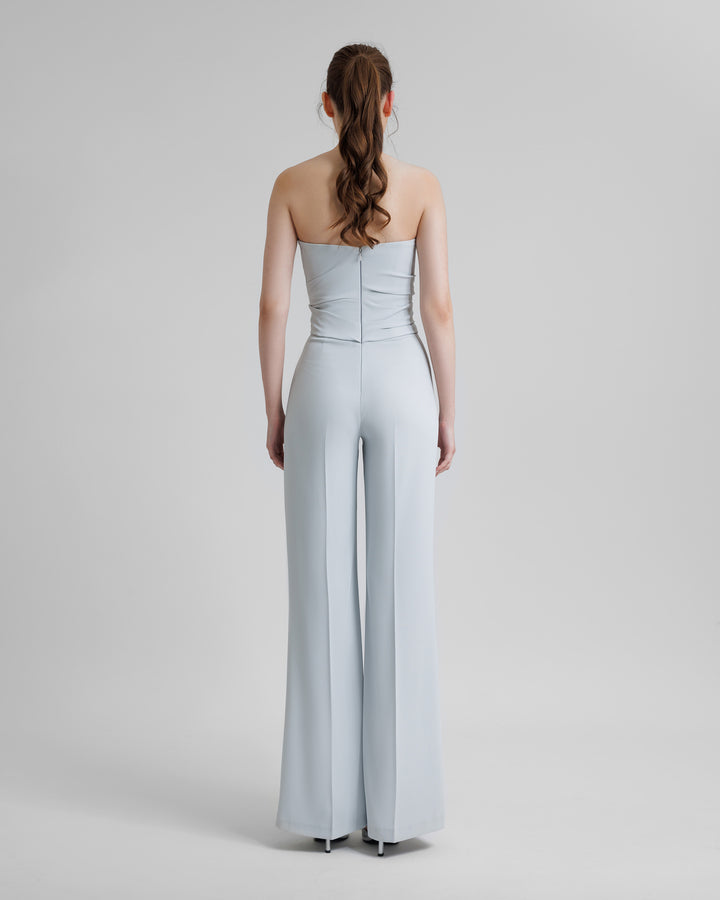 The back of a strapless grey jumpsuit featuring draping on the waist.