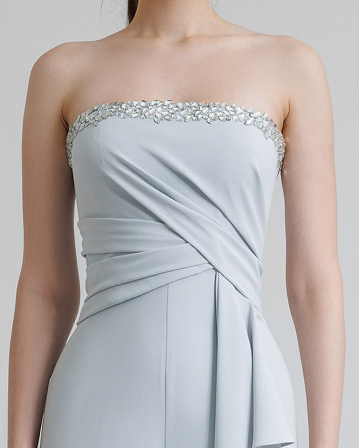 A close-up of a strapless grey jumpsuit featuring a beaded neckline and draping on the waist.