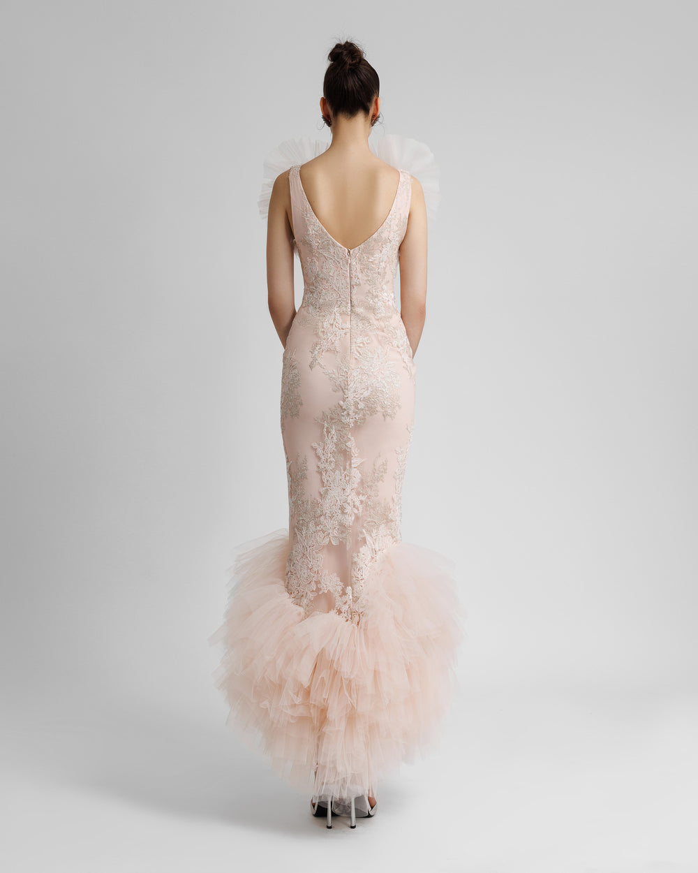 The back of a fully embroidered lace long blush evening dress with rushed tulle on the neckline, shoulders line and hemline with a slightly open back.