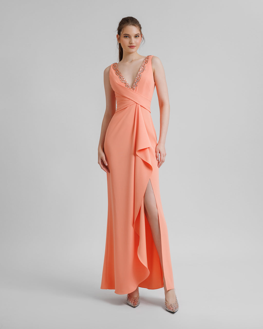 A peach beaded v-neckline evening dress featuring draping on the waist and a slit on the side.