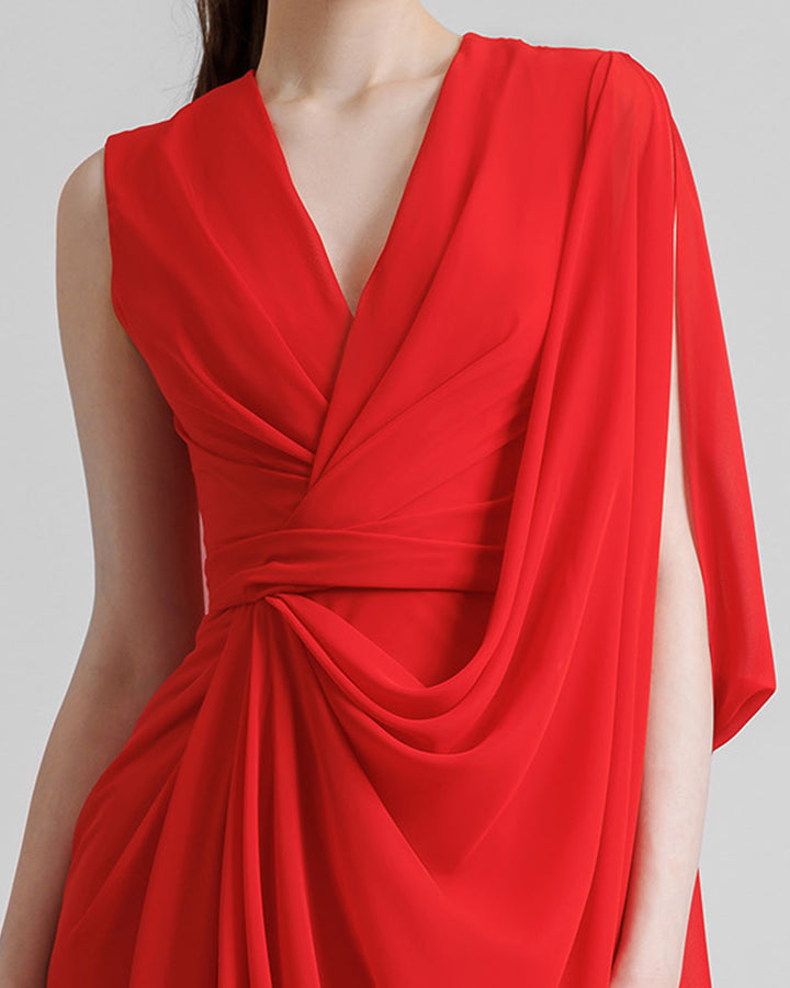 A close-up of an asymmetrical V-neckline, red evening dress with draping details, and a long cape-like sleeves.