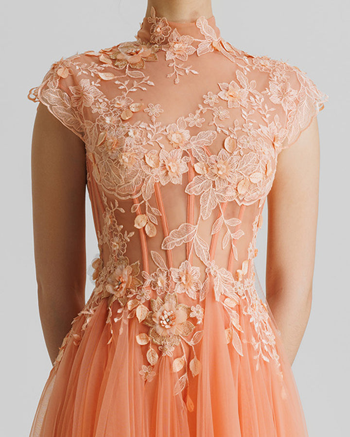 A close-up of a fully embellished floral see-through corset evening dress in peach color with a high-collar and flared tulle skirt.