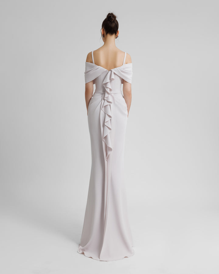 The back of a slim-cut crepe lilac evening dress with an off shoulders bow-like neckline with thin straps, a belt on the waist, and ruffles on the back.