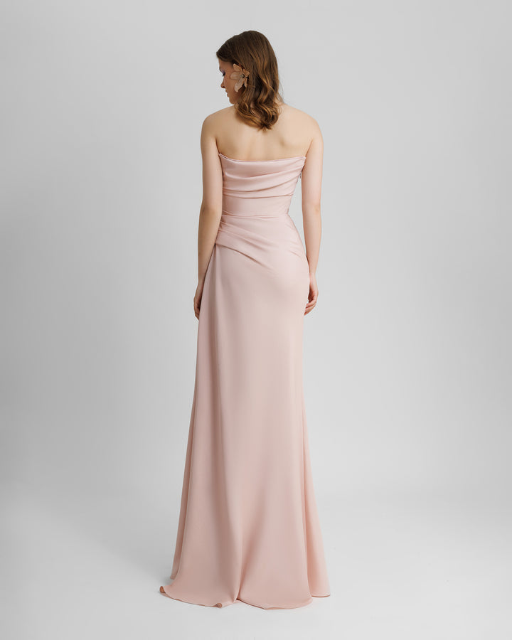 The back of a strapless, straight cut blush long evening dress, with bust line, and some draping details from the bust going down the waist.