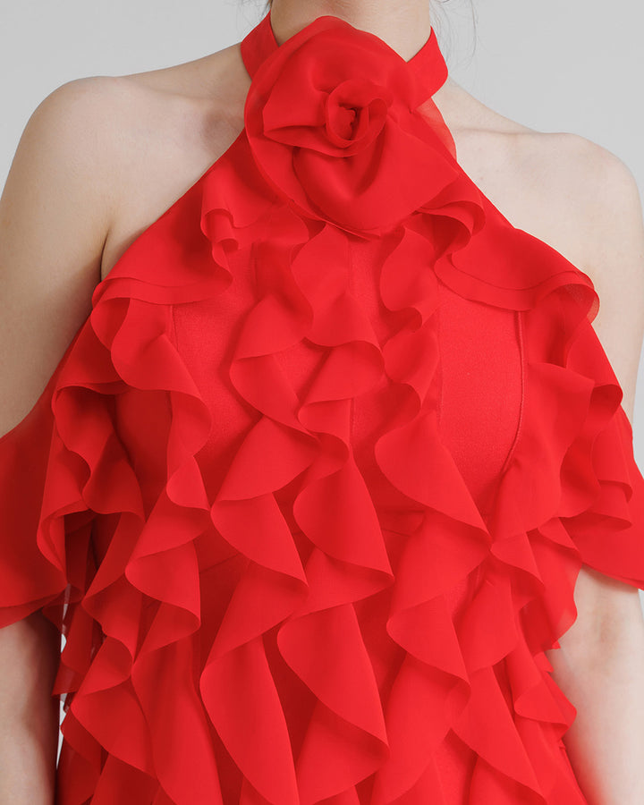 A close-up of a halter-neck red evening dress featuring dropped sleeves and laser-cut embellishments.