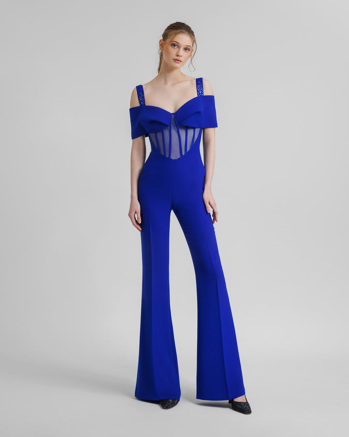 A flared royal blue jumpsuit featuring a see-through corset with a bow off-shoulders design and beaded straps.