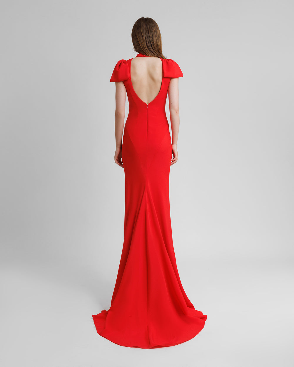 The back of a slim-cut long red evening dress featuring bows on the shoulders and an open back.