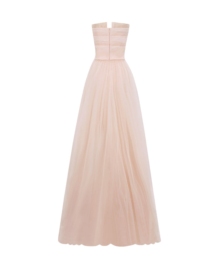 The back of a strapless, flared long blush evening dress with draping details on the bust line.