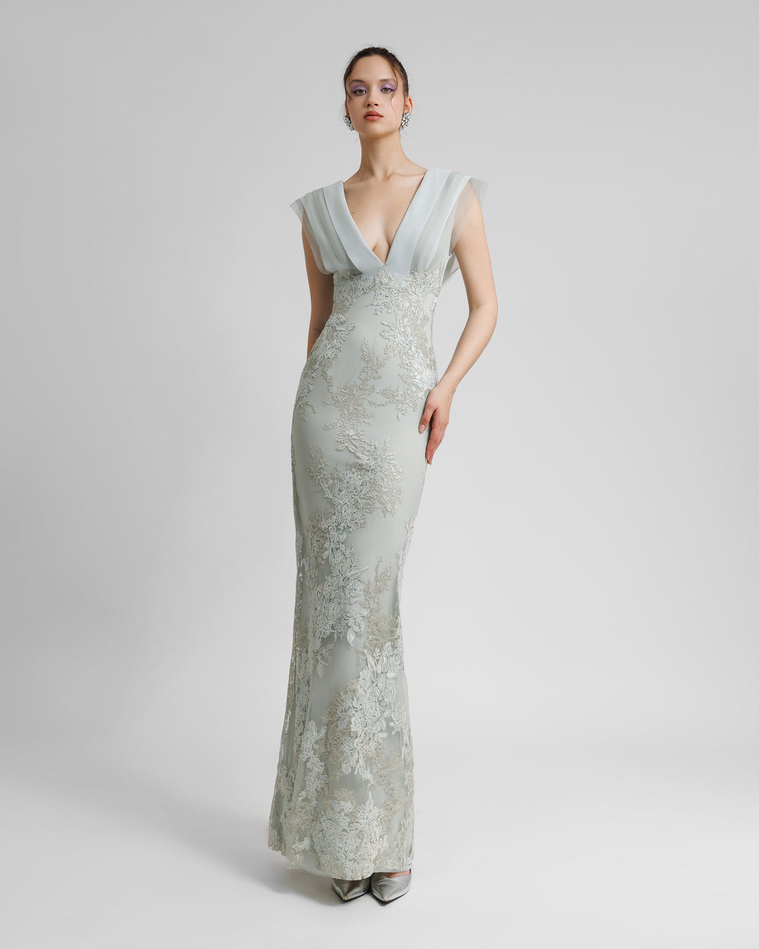 A fully embellished deep V-shaped neckline grey evening dress with draping details on the bust and a slit on the back.