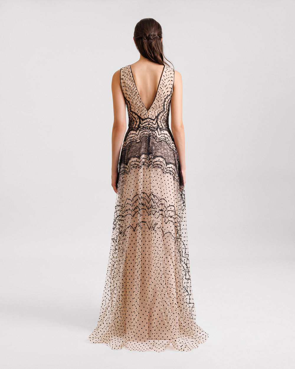 The back of an embroidered V-neckline black and beige evening dress with a low V-cut back.