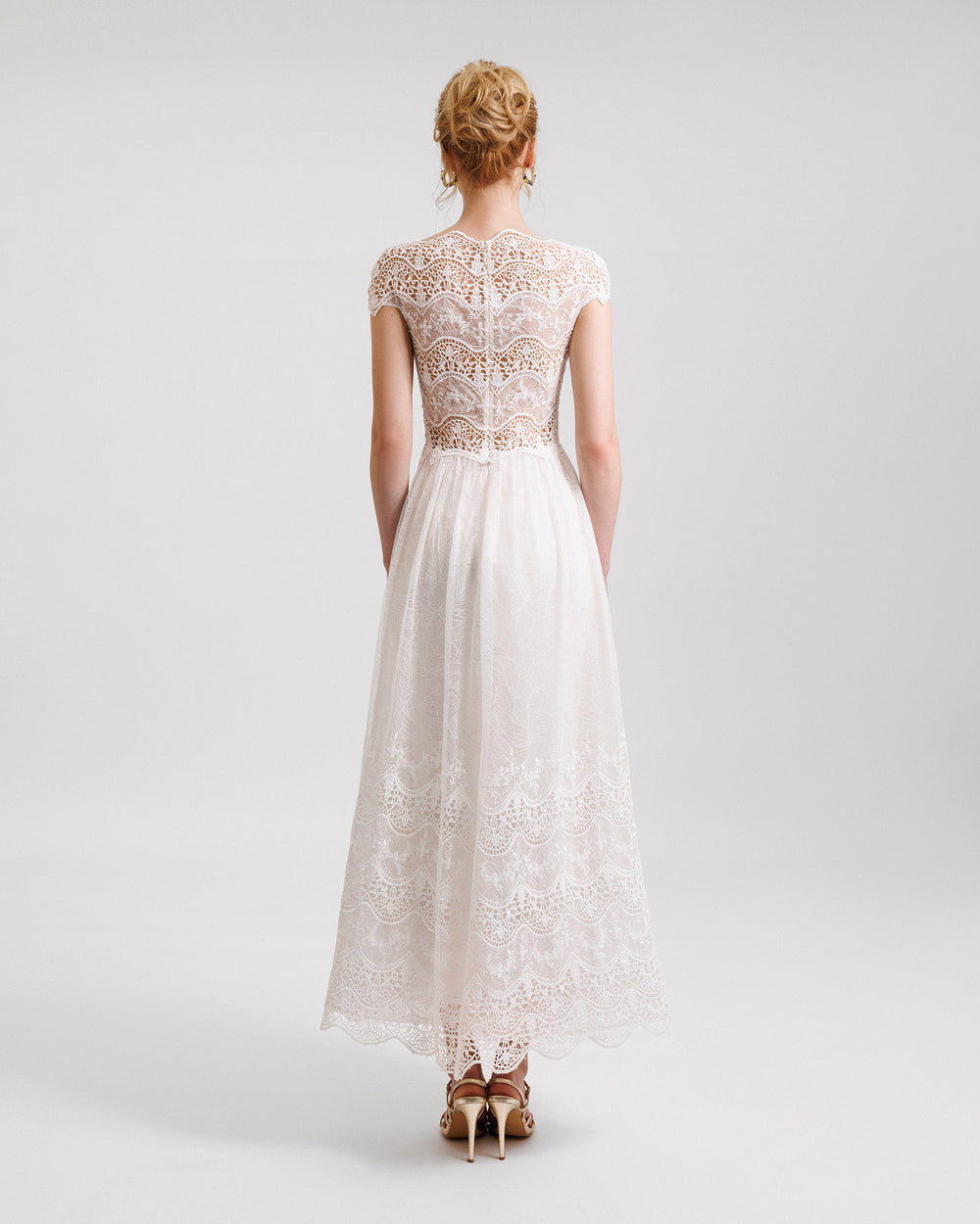 A short-sleeves white midi dress in embroidered lace with a see-through back.