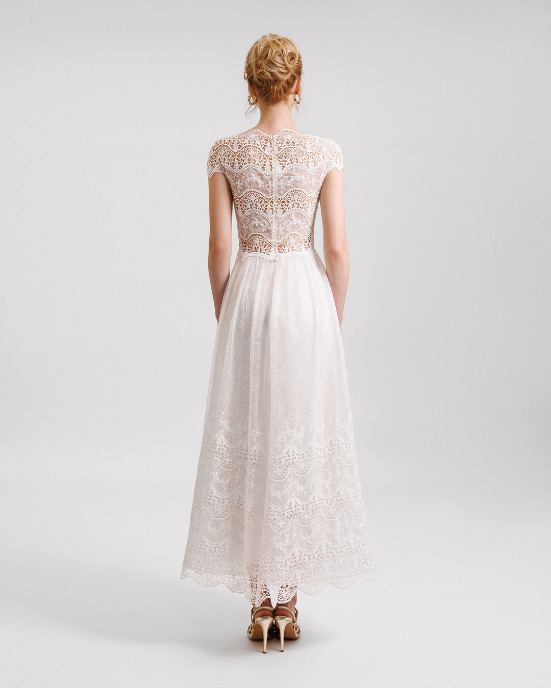 A short-sleeves white midi dress in embroidered lace with a see-through back.