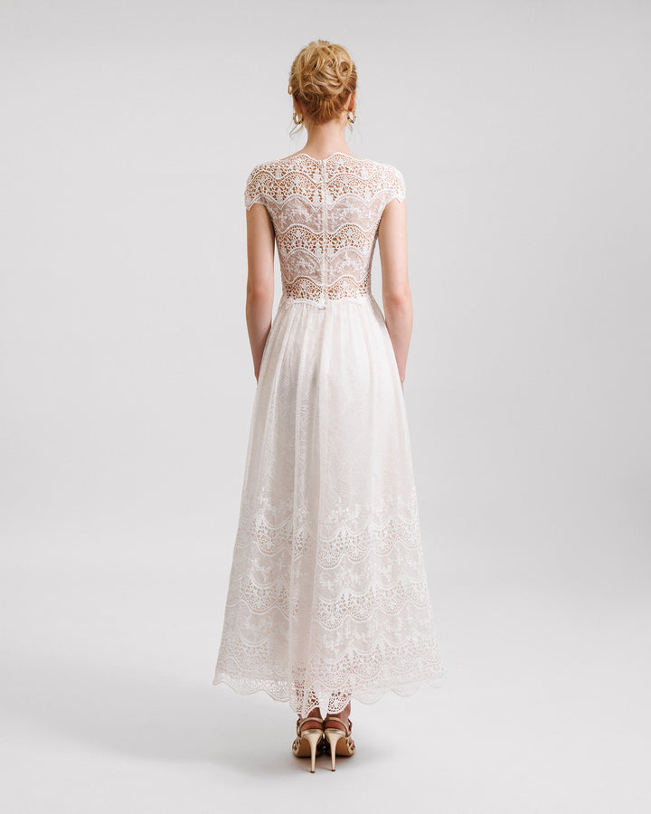 A short-sleeves white midi dress in embroidered lace with a see-through back.