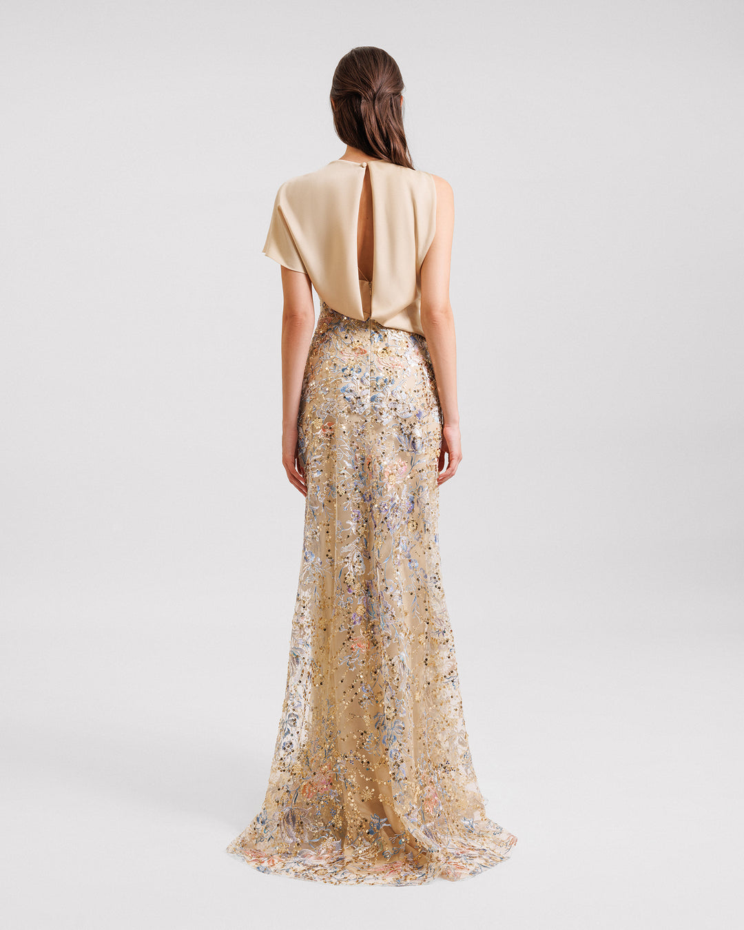 The back of a long evening dress featuring a draped satin corset with a back cut out and a beaded embroidery skirt.