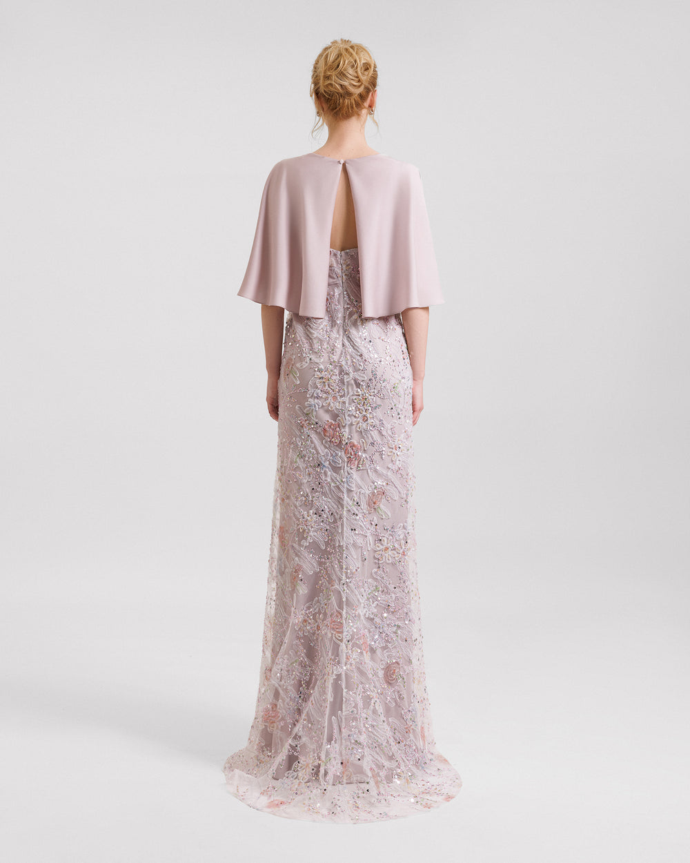 The back of a beaded embroidery evening dress in dusty pink with cape-like sleeves.