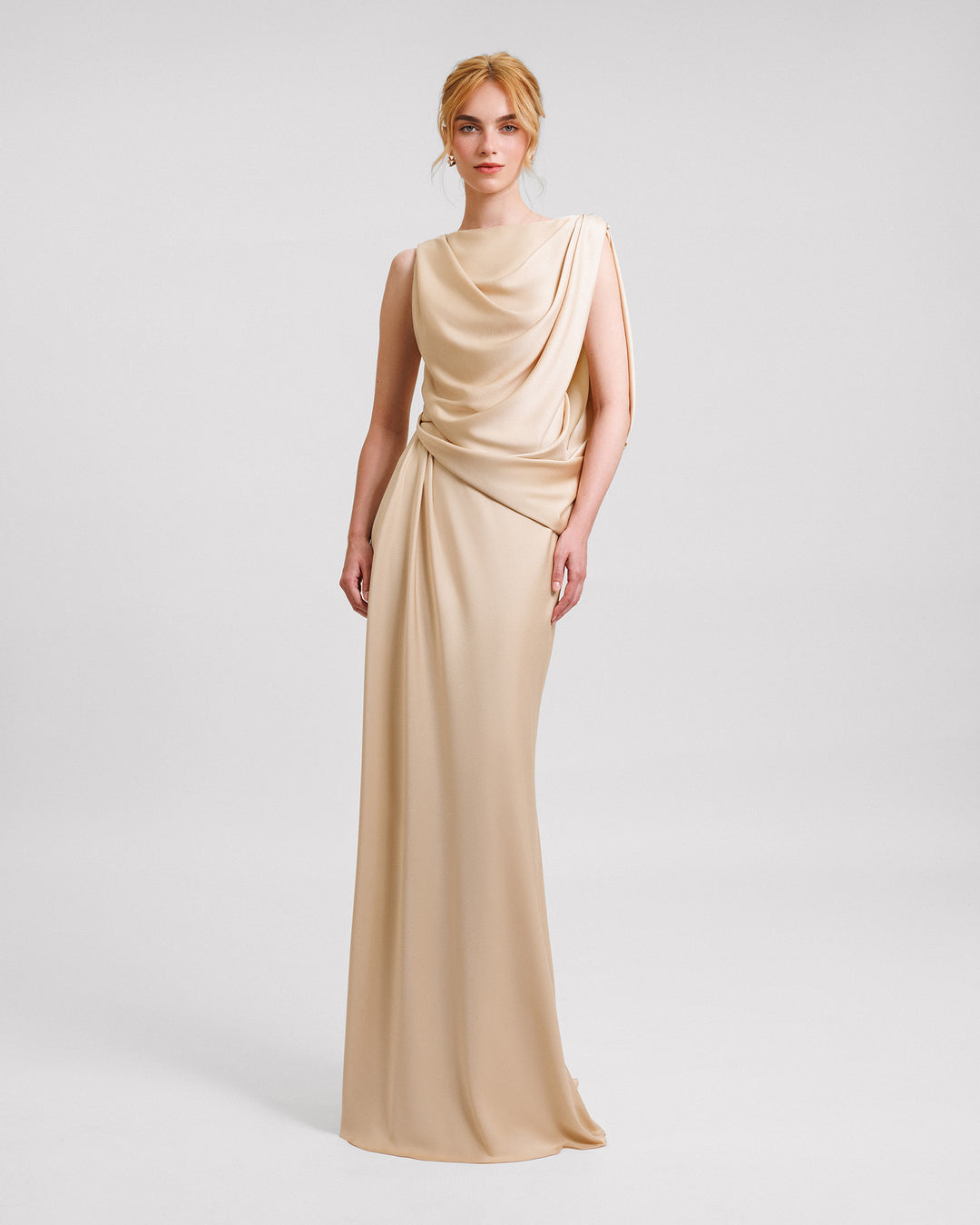 An asymmetrical draped evening dress in champagne satin fabric.