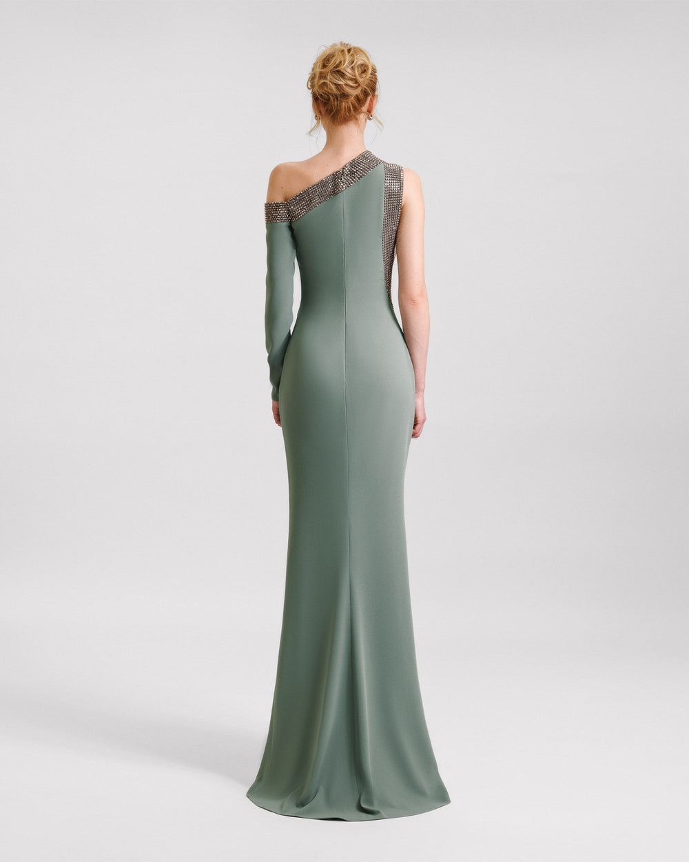 The back of a stone embellished asymmetrical neckline evening dress in sage color.