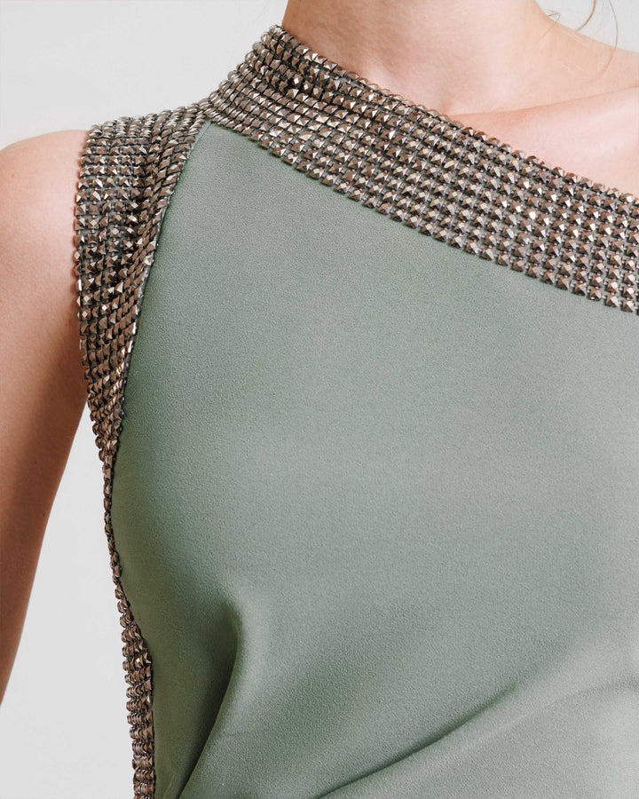 A close-up of a stone embellished sage evening dress.