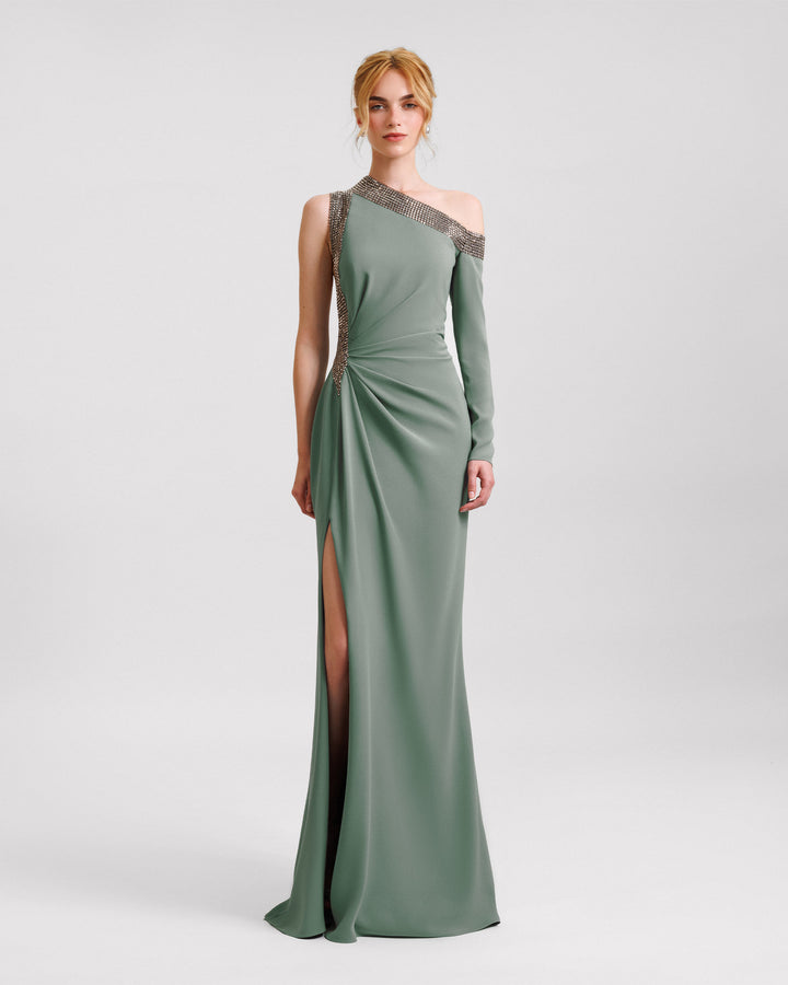 A stone embellished asymmetrical neckline dress with draping on the waistline and an open slit on the side.