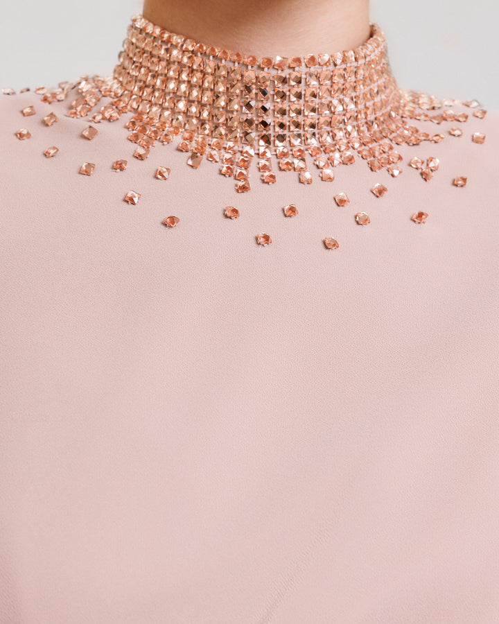 A close-up of a blush evening dress featuring a stone embellished collar.