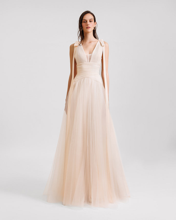 A V-neckline evening dress in cream tulle with bows on the shoulders and a draped waistline.