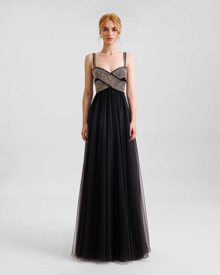 A long black evening dress in tulle with a bow-like stone embellished top.