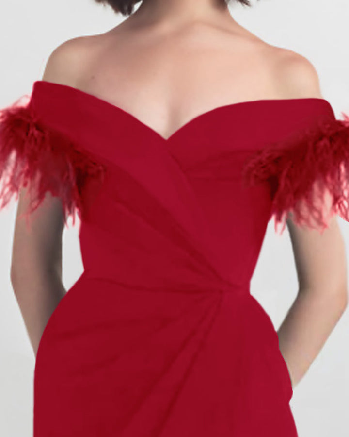 A close-up of a feathers off shoulder slim cut long red dress with draping details on the waist.