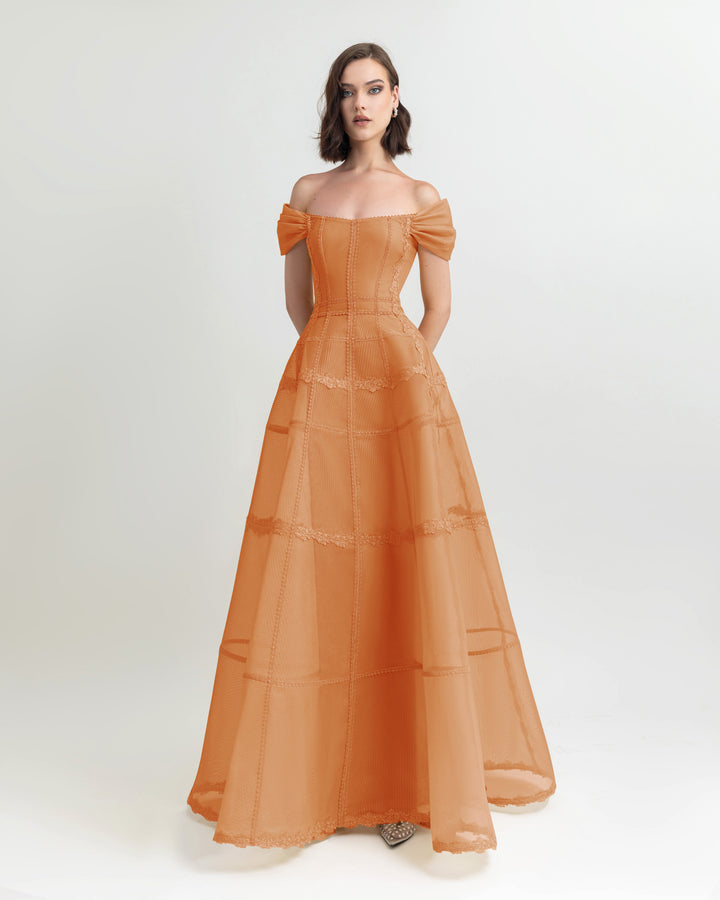 An off-shoulders corset mesh dress in orange with a long wide skirt.