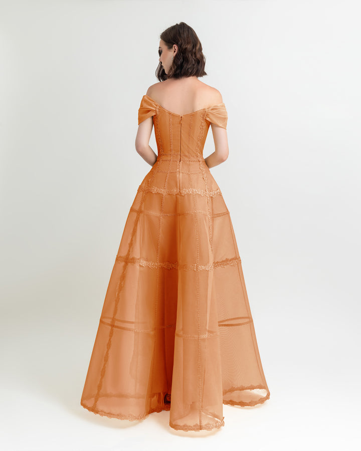 The back of an off-shoulders corset mesh dress in orange with a long wide skirt.